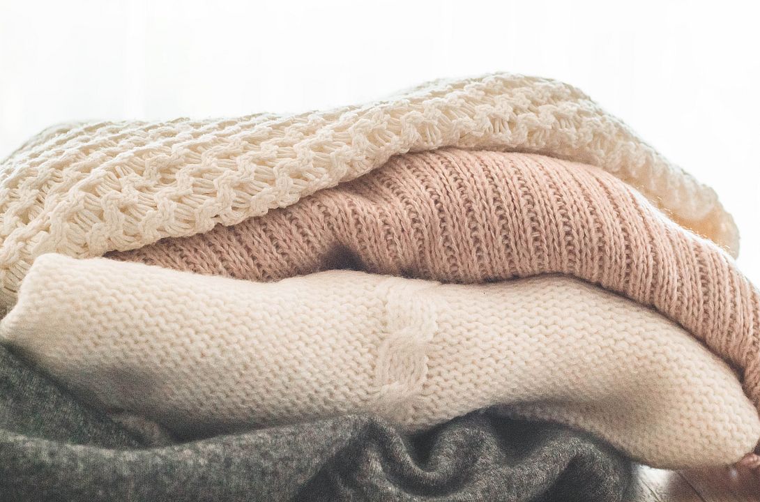A stack of knitted sweaters in the interior of the living room. The concept of autumn winter comfort.