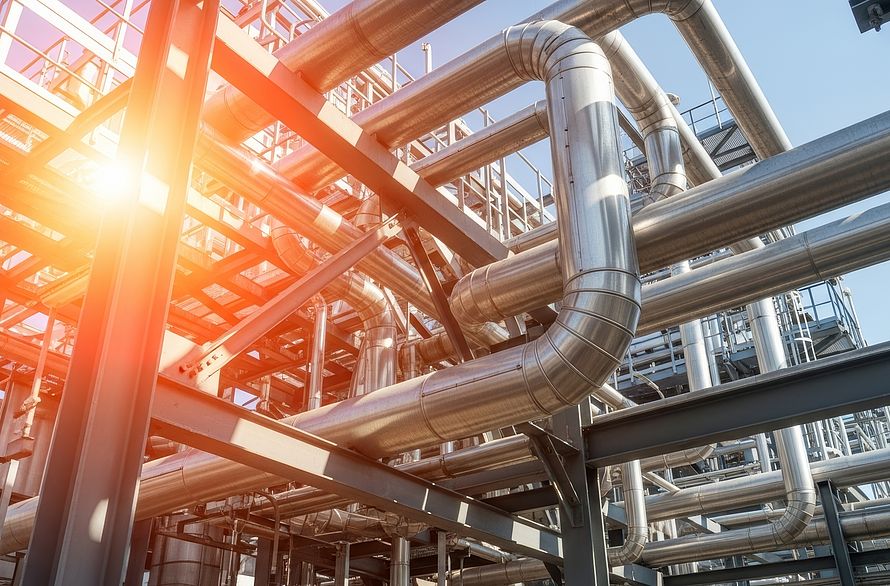 Industrial pipes and structures under bright sun.